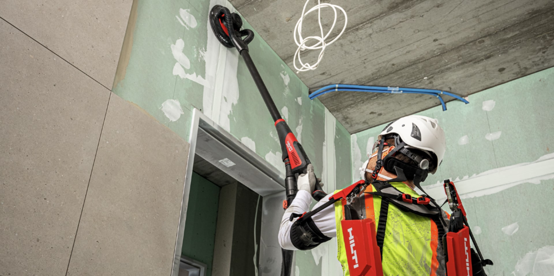 Bild på hantverkare som slipar en vägg utrustad med exoskelett
