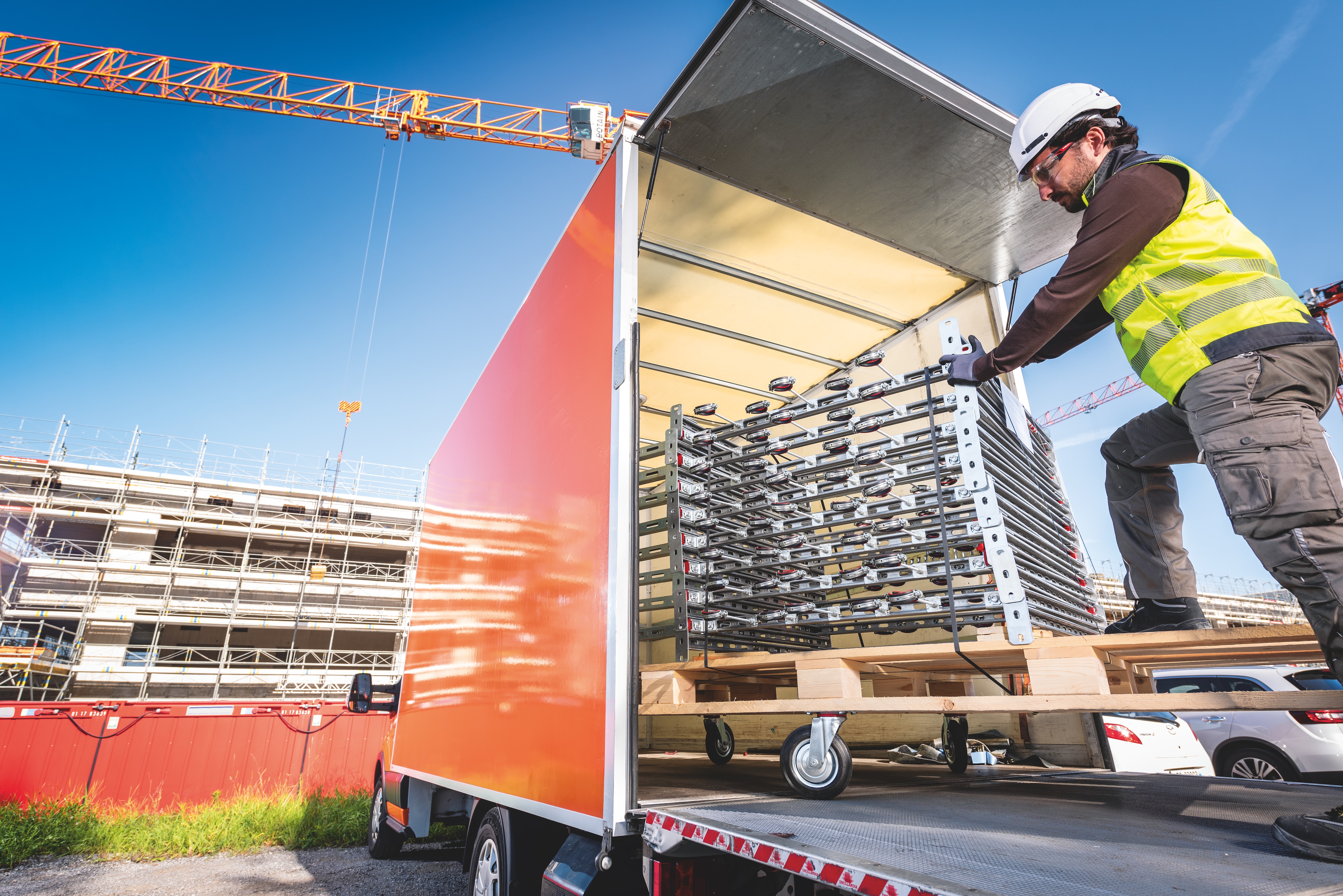 Arbetare som lastar av prefabricerade byggbara moduler från en lastbil