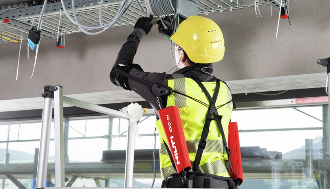 Elektriker med exoskelett arbetar med kablar ovanför huvudet