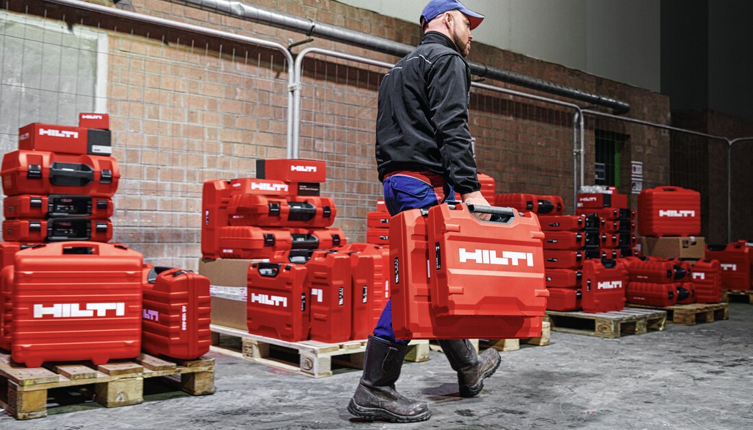Man bärande på verktygslådor i ett lager fullt med verktygslådor
