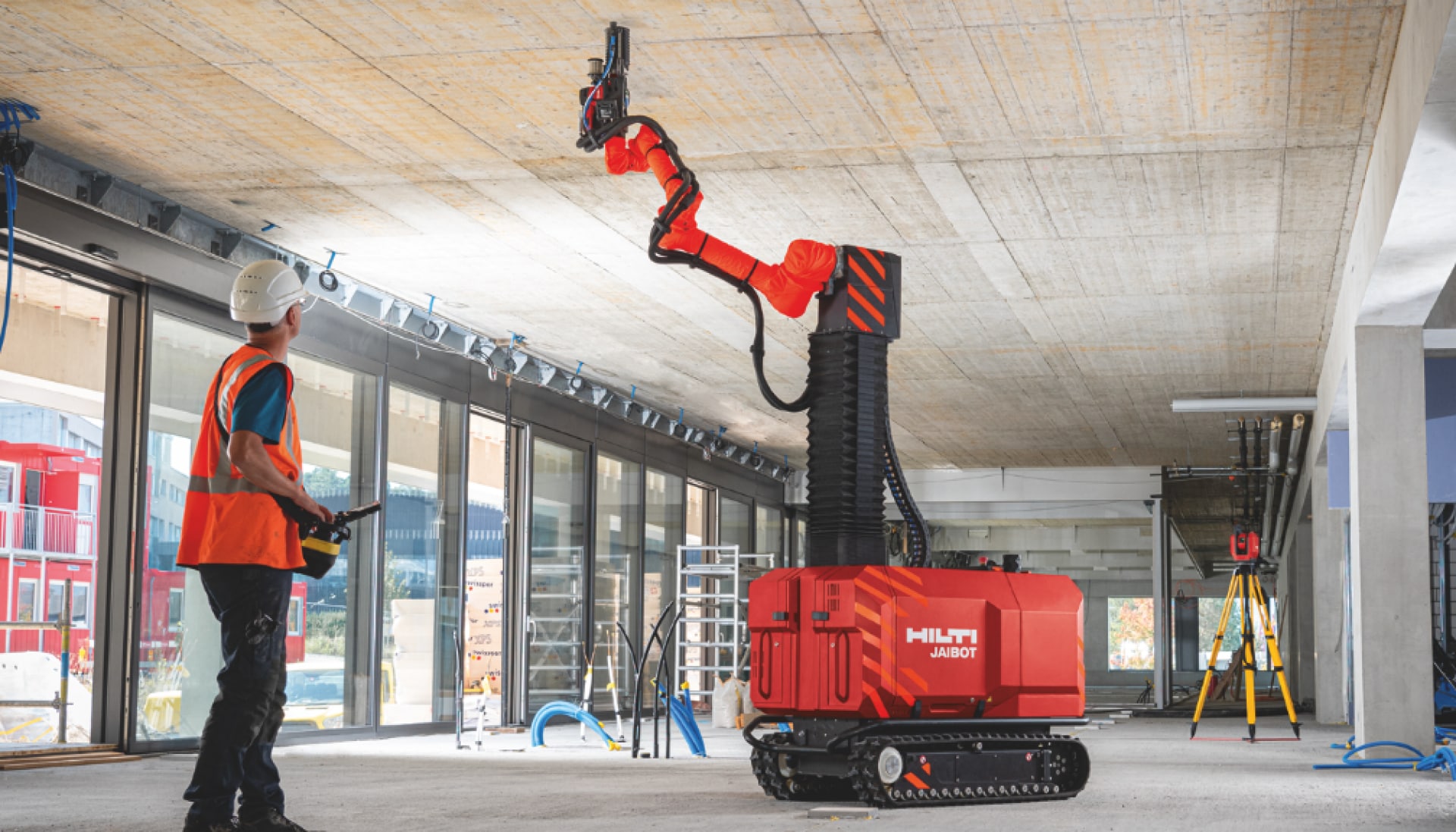 Byggnadsarbetare arbetar säkert när de styr roboten Jaibot under tiden den borrar hål i taket på en arbetsplats