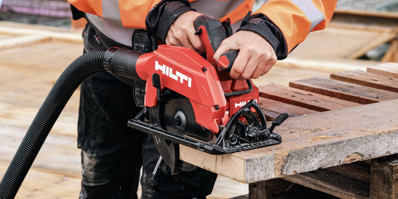 person using a red Hilti tool to cut wood