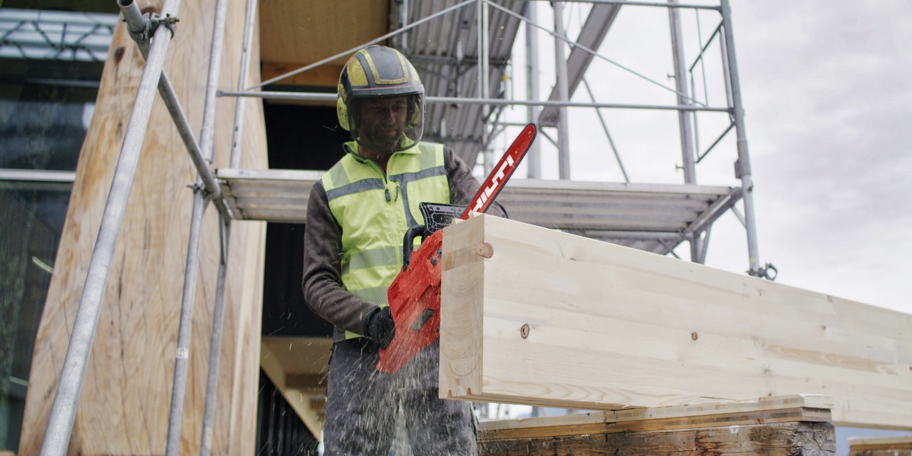 Arbetare framför massivträ med en motorsåg i handen